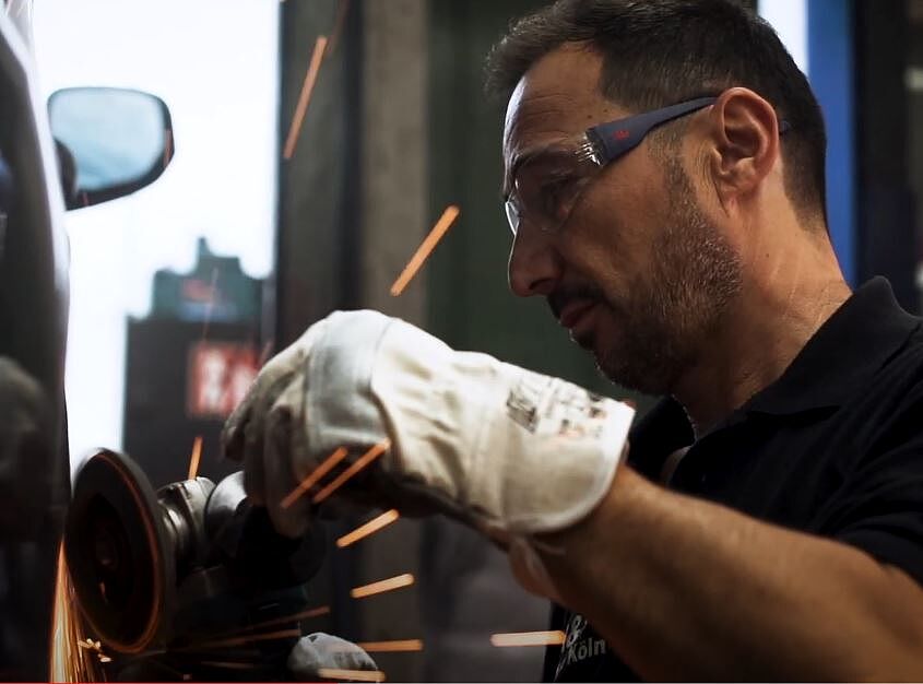 Eine Person führt Schleifarbeiten an einem Fahrzeug durch