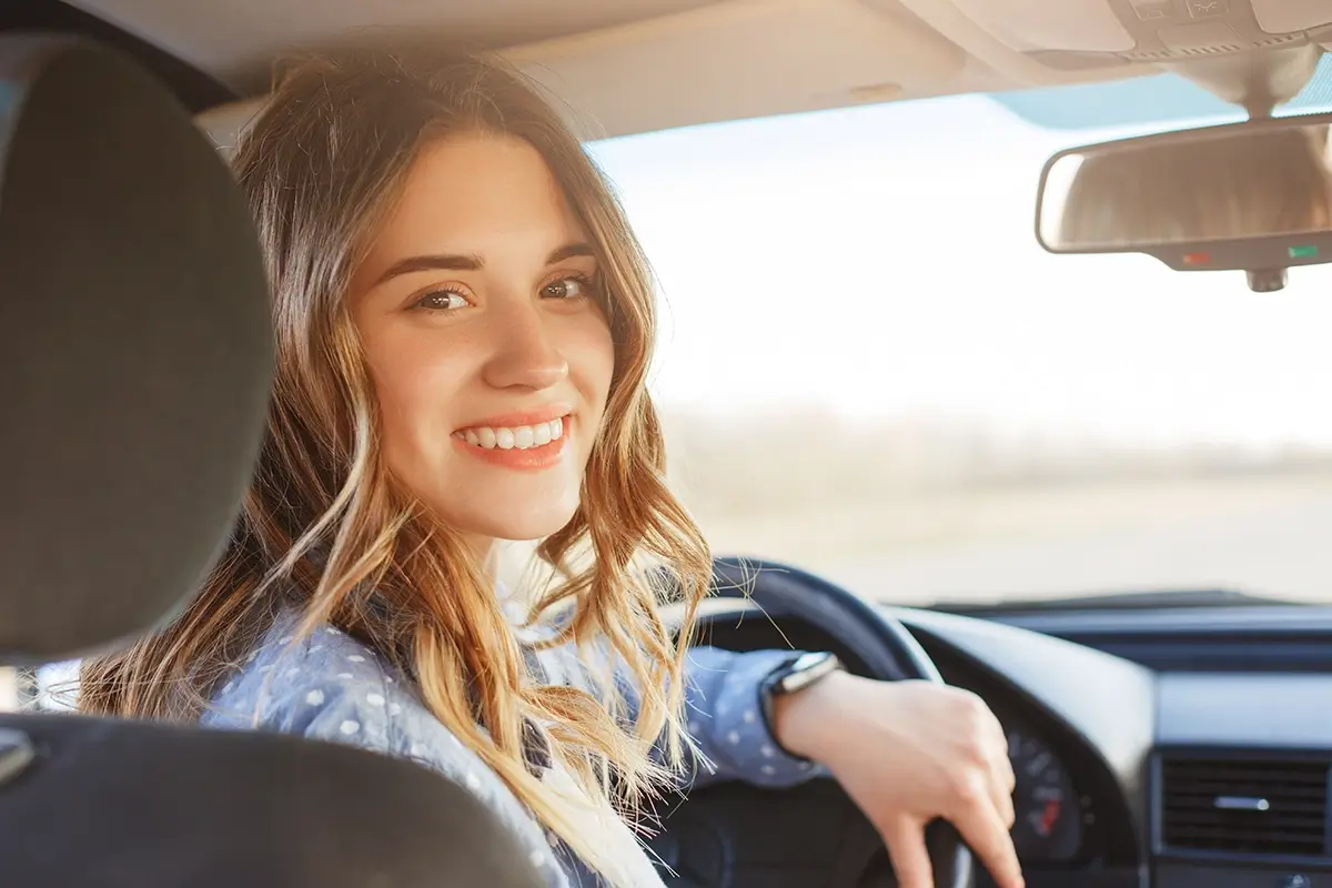 Eine Person am Steuer eines Fahrzeugs lächelt in die Kamera