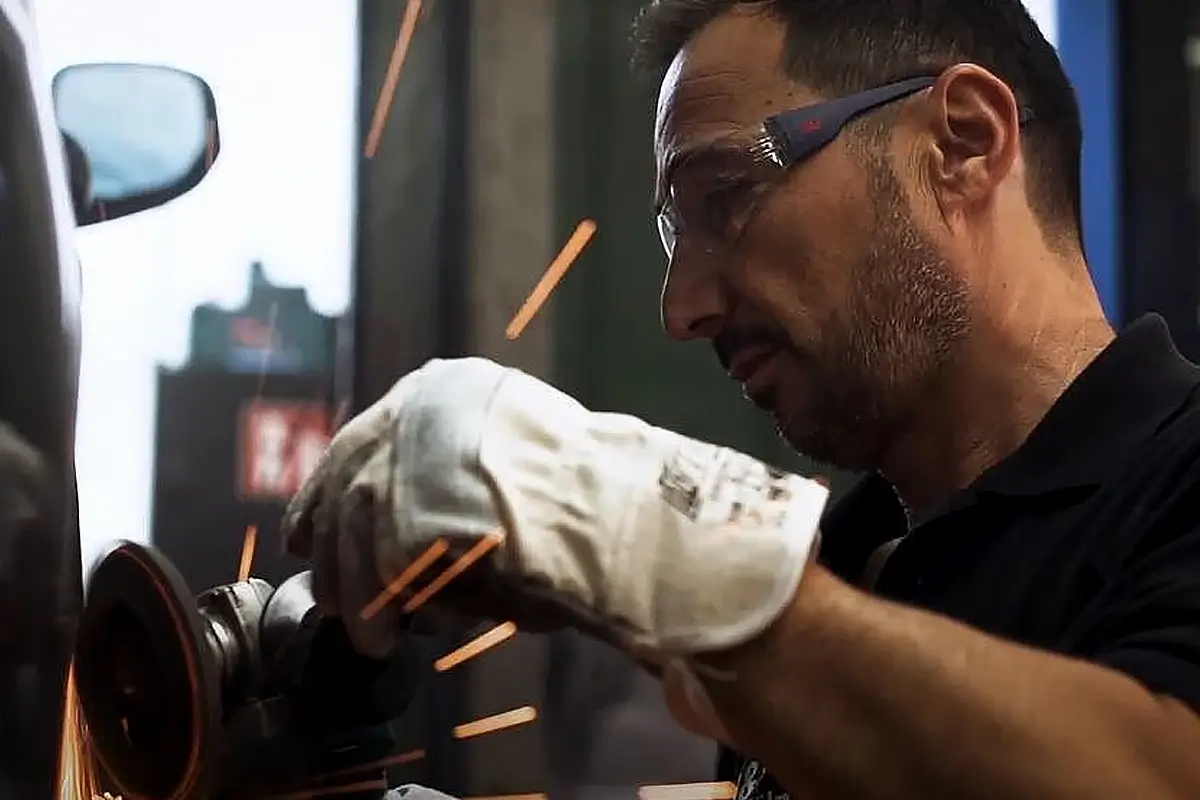 Eine Person führt Schleifarbeiten an einem Fahrzeug durch