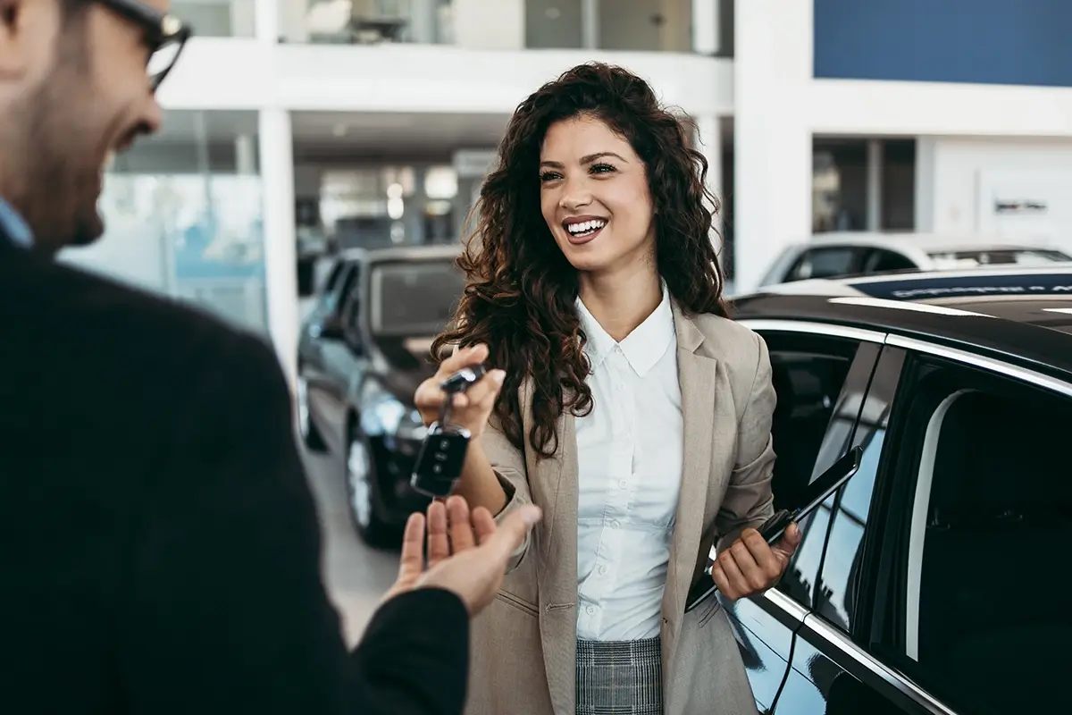 Eine Person überreicht im Autohaus einer anderen Person einen Autoschlüssel