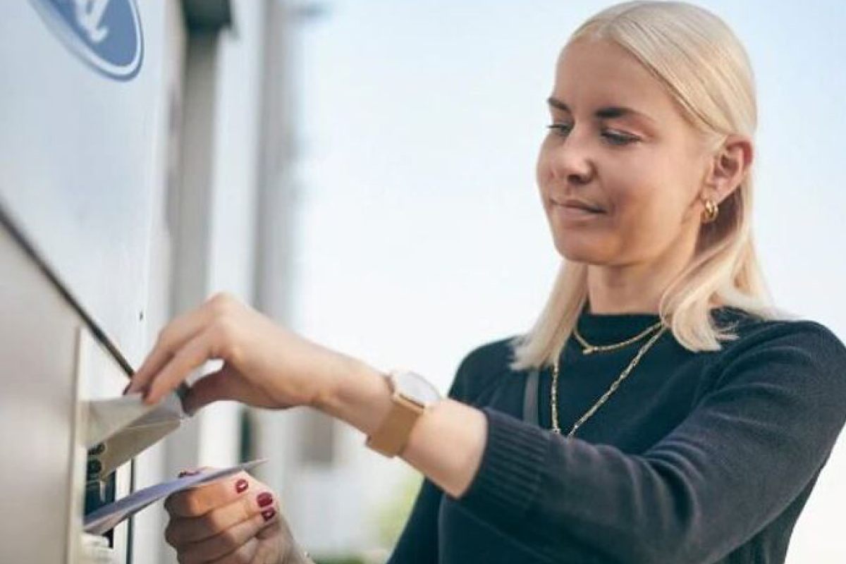 Eine Person wirft einen Brief in ein Postfach