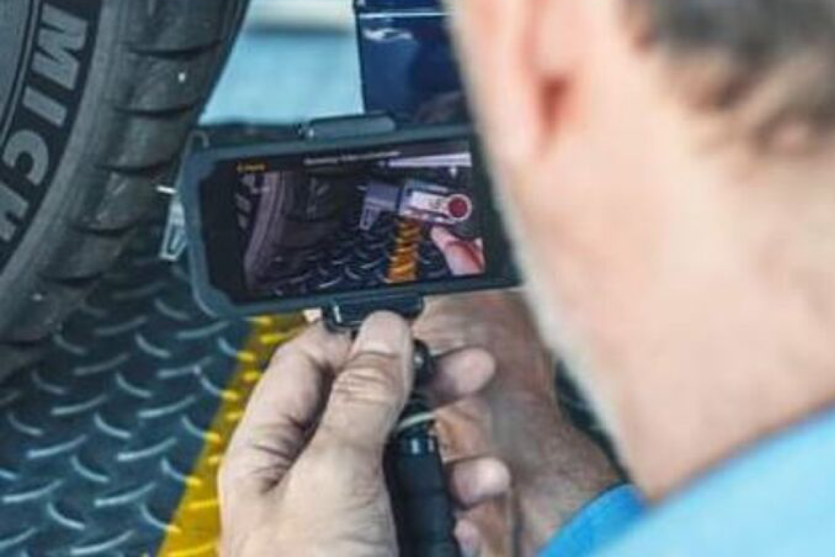 Eine Person zeigt mit einem aufnehmenden Handy auf einen Autoreifen