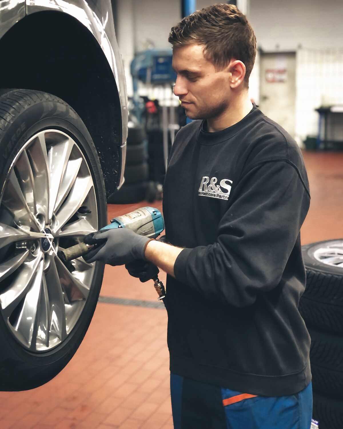 Zu sehen ist ein Mitarbeiter beim Reifenwechsel