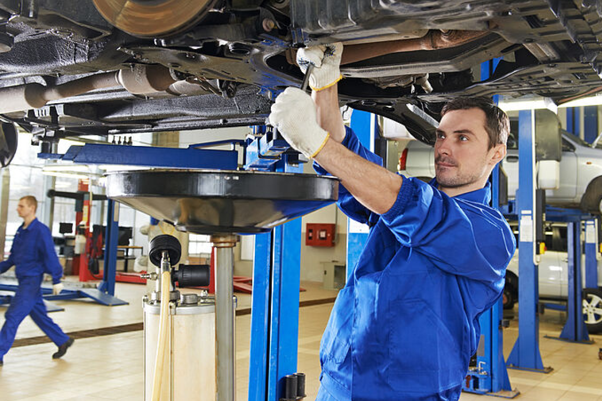 Eine Person führt Arbeiten am Unterboden eines Fahrzeugs durch