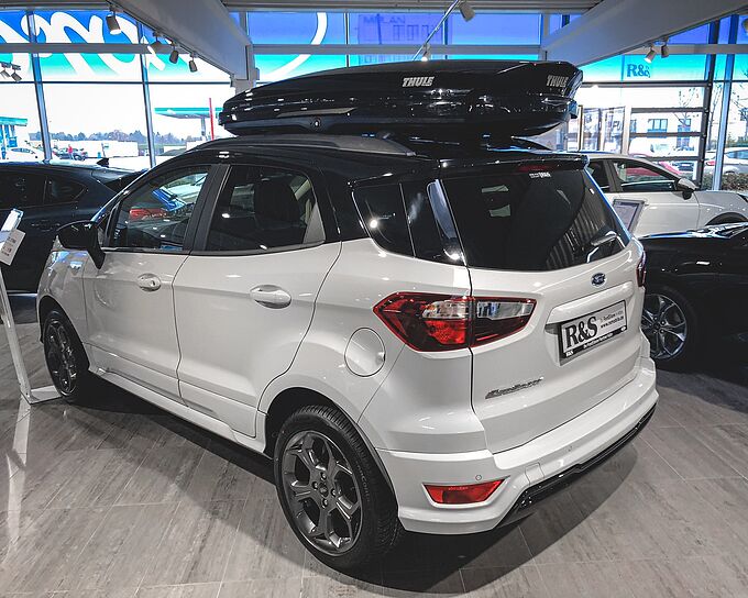 Zu sehen ist ein Fahrzeug mit einer Dachbox auf dem Dach